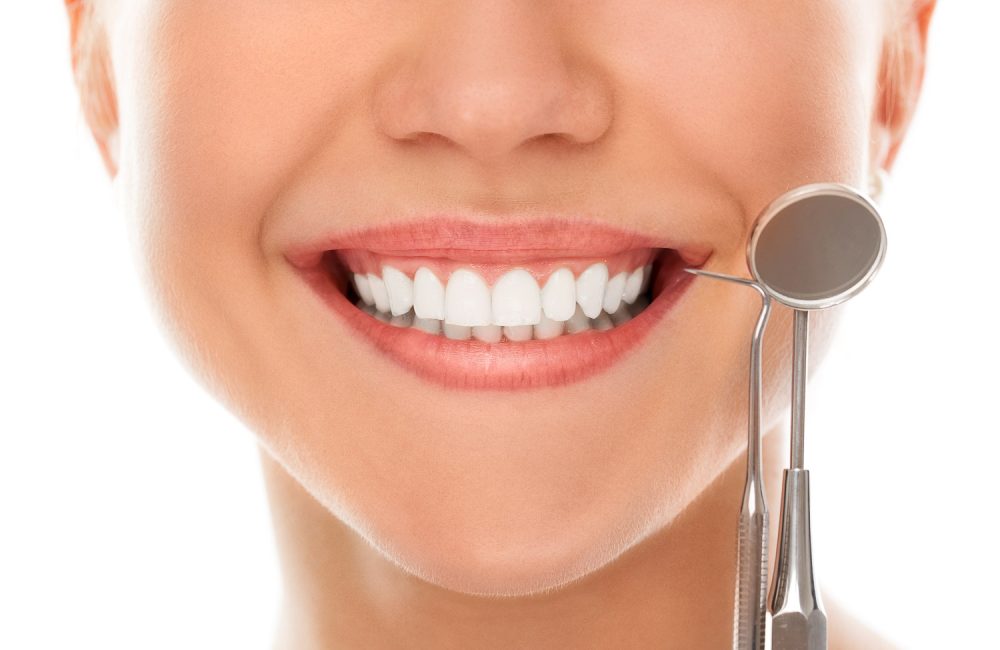 A woman is smiling while being at the dentist